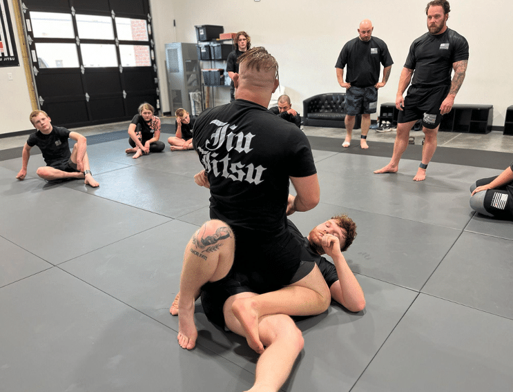 A coach controls a student from the top position while teammates watch and learn